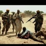 Militia chief with armed guards and restrained journalist in Darfur.