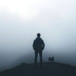 Person at foggy crossroads, contemplating different paths.