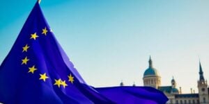 European Union flag waving with iconic landmarks in background.