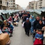 Displaced families in a crowded street during a crisis.