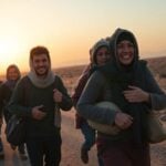 Syrian refugees walking home, carrying their belongings.