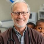 Dr. Sack smiling with children and medical equipment around.