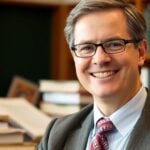 Todd Gingrich smiling in an academic setting with books.