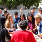 Diverse community members collaborating outdoors in a sunny setting.