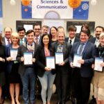 Diverse group celebrating science communication excellence with awards.