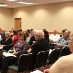 Community members discussing new hospital progress at meeting.