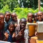 Children gathering around solar-powered water pumps in Ghana.