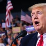 Donald Trump speaking at a rally with enthusiastic supporters.