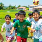 Children playing sports in Thailand, smiling and active.