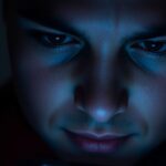 Person illuminated by a phone screen in dim light.