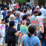 Diverse artists collaborating in a colorful outdoor event.