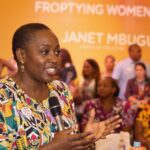 Janet Mbugua speaking with diverse women in lively discussion.