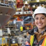 A woman in safety gear at a shipyard.