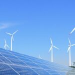 Solar panels and wind turbines in a green African landscape.