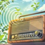 Vintage radio with sound waves among green leaves.