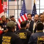Workers united at a trade conference, flags in background.