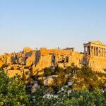 Sunset view of Acropolis with ancient columns and trees.