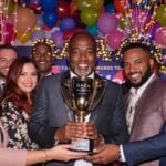 Diverse winners holding a trophy at the awards ceremony.