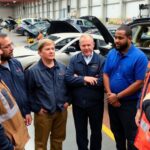 Diverse factory workers discussing auto job security together.