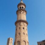 Reconstructed Al-Hadba Minaret against a clear blue sky.