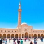 Al-Nouri Mosque Complex with leaning minaret and visitors.