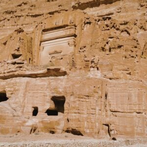 Sandstone cliff with carved ancient tomb facades and a doorway in Petra-like ruins