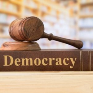 Gavel resting on a book labeled Democracy, symbolizing justice and the rule of law.