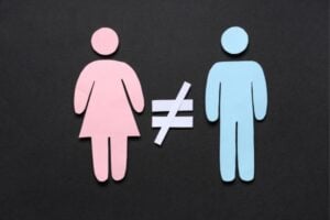 Pink female and blue male silhouettes with a not-equal sign between them, illustrating gender inequality.