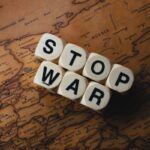 Blocks with letters S T O P W A R spell out 'STOP WAR' resting on a vintage map, conveying an anti-war message.