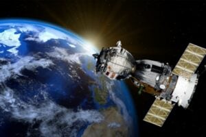 Satellite in orbit around Earth with bright sun glare at the horizon behind it