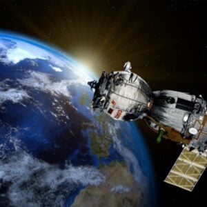 Satellite in orbit around Earth with bright sun glare at the horizon behind it