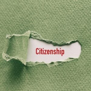 Torn green paper revealing the word Citizenship in red on white background.