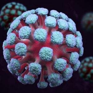 3D rendering of a coronavirus particle with blue-green spike proteins on a red core against a dark background