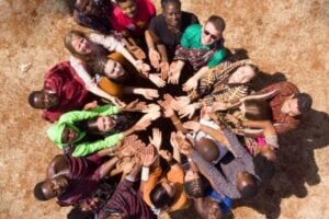 Diverse group forming a circle from above, hands joined in the center to symbolize teamwork and unity.