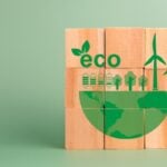 Wooden blocks form a green eco illustration with wind turbines, trees and a globe.