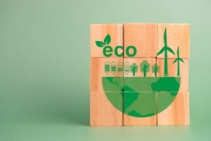 Wooden blocks form a green eco illustration with wind turbines, trees and a globe.