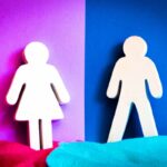 White paper cutouts of a girl and a boy stand on opposite colored backgrounds (pink left, blue right) with a vertical color split between them, suggesting gender division.