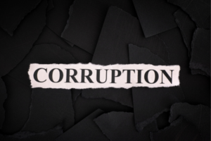 Pink torn paper strip with the word 'CORRUPTION' on a dark, torn-paper background.