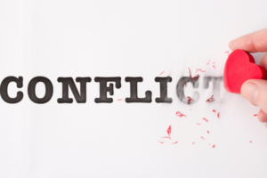 Hand holding a red heart erases the word 'CONFLICT,' symbolizing ending conflict or choosing peace.
