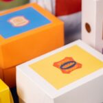 Colorful toy boxes with blue, yellow, and orange lids stacked together on a table.