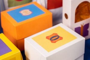 Colorful toy boxes with blue, yellow, and orange lids stacked together on a table.