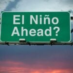 Green overhead road sign reading 'El Niño Ahead?' against a cloudy sky.