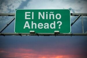 Green overhead road sign reading 'El Niño Ahead?' against a cloudy sky.