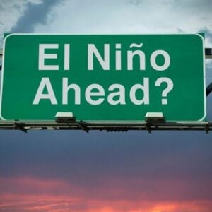 Green overhead road sign reading 'El Niño Ahead?' against a cloudy sky.