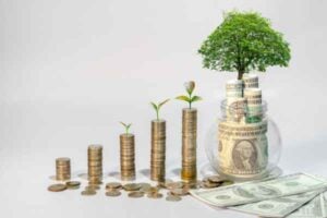 Coin stacks rise left to right with small plants, and a tree grows from a jar of cash beside scattered bills—symbolizing financial growth and investment.