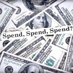 Pile of US $100 bills with a banner reading 'Spend, Spend, Spend?'.