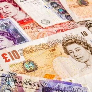 Pile of assorted British pound banknotes (£10, £20, £50) overlapping in a colorful collage.
